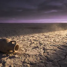 Deserto de pedra ao amanhecer, com uma vasilha de barro vazia em primeiro plano e luz dourada rasante